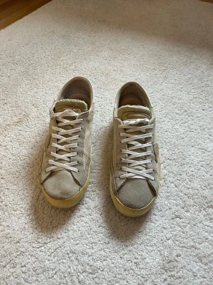Beige sneakers i mocka med vita detaljer - Säljer ett par Philippe Model sneakers i beige/vit färgkombination. Klassisk och stilren modell som passar till det mesta. Skorna är använda men fortfarande i bra skick med mycket liv kvar.  * Märke: Philippe Model * Storlek: 40 * Färg: Beige / vit * Skick: Bra skick * Bekväma och stilrena premium-sneakers  Normalt slitage finns på sula och ovandel enligt bilder, men helhetsintrycket är fortfarande väldigt fint.