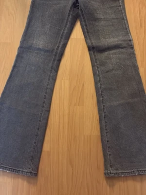Grå bootcut jeans från Abrand Jeans - Snygga grå bootcut jeans från Abrand Jeans i mjuk bomull. Jeansen har klassisk femficksmodell, hög midja och vida ben. Perfekta för dig som gillar en retroinspirerad look och vill ha ett par bekväma jeans med cool tvätt. 