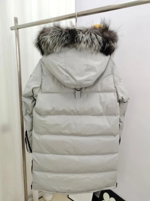  Moose knuckles Ljusgrå lång dunjacka med pälskant - Ljusgrå lång dunjacka med stor huva och fluffig pälskant i svart och grått. Jackan har svarta detaljer, dragkedja och tryckknappar framtill samt flera innerfickor. Perfekt för kalla vinterdagar och riktigt varm.