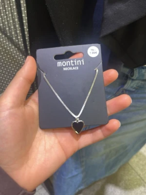 Silverhalsband med hjärthänge Montini - Snyggt silverfärgat halsband från Montini med ett hjärtformat hänge. Kedjan är tunn och elegant, perfekt för att ge en söt touch till din outfit. Passar dig som gillar stilrena och klassiska smycken.