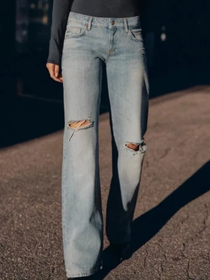 Ljusblåa raka jeans med slitningar - Säljer ett par ljusblå jeans med raka ben och slitna hål vid knäna. Jeansen har klassisk femficksdesign och hög midja. Perfekta för en avslappnad och trendig look.