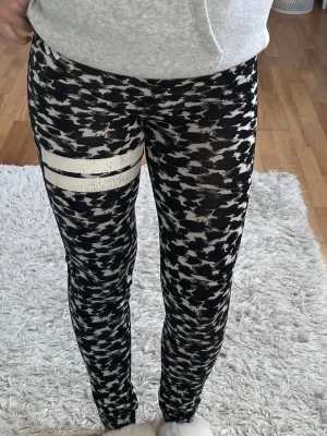 Svarta/ vita träningstights  - Snygga leggings från Lager 157 i svartvitt abstrakt mönster med två vita ränder på ena benet. Stretchigt material som sitter tight och bekvämt. De är i storlek 160, men skulle säga att dem är en S/XS