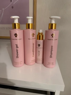 Heart for Heart hår- och kroppsvårdset - Säljer ett set med duschgel, balsam, hårolja och schampo från Heart for Heart. Produkterna kommer i rosa flaskor med gulddetaljer och pumpfunktion. Perfekt för dig som vill ha ett matchande och stilrent kit i badrummet.