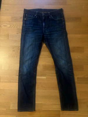 Vintage levi jeans  - Snygga mörkblå slim fit jeans med klassisk femficksdesign och subtila slitningar. Jeansen har raka ben och är tillverkade i ett robust denimtyg som ger en tidlös look. Perfekta för dig som gillar en enkel men stilren stil.