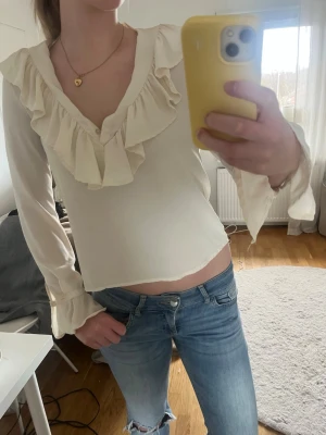 Vit blus med volang och v-ringning - Säljer min snygga vita blus med v-ringning och stora volanger längs halsen. Blusen är från zara och är i väldigt bra skick. Blusen går o bära på olika sätt som det syns på bilderna.