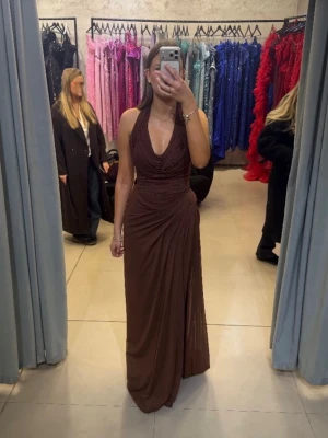 Brun lång halterneckklänning - Tänkte kolla intresset på denna bruna halterneckklänning. Ska använda den balen 2026 och går därför intr att köpa än. Skriv vid intresse eller om ni redan nu vill reservera. Storlek 36/38.        Pris: 5300kr