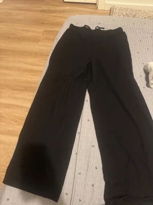 Svarta mjukisbyxor från Amisu - Svarta mjukisbyxor från Amisu med bred resår i midjan och raka ben. Tillverkade i ett mjukt och stretchigt material som känns skönt mot huden. Perfekta för chill dagar eller när du vill ha det extra bekvämt.