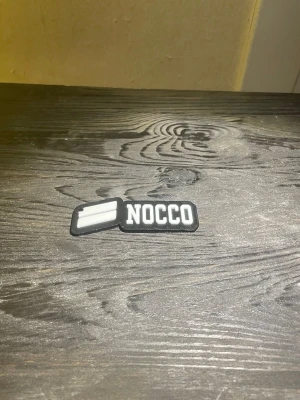 Svart NOCCO  - Säljer ett NOCCO-logga. Kan användas som nyckelring eller kan limmas på kläderna med rätt typ av lim. Billigare vid snabb affär.