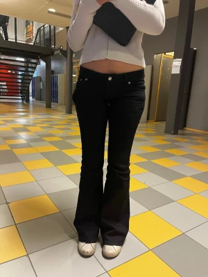 Svarta bootcut jeans med jätte låg midja - Snygga svarta bootcut jeans med låg midja och klassisk femficksdesign. Jeansen har utsvängda ben och sitter tight över höfterna. Perfekta för en trendig och avslappnad look. Materialet är stretchigt denim för extra komfort. Det är perfecta för mig o jag är 175 cm
