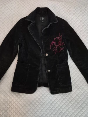 Machester kavaj figurnära - Väldigt fin kavaj i manchester tyg från tidigt 2000-tal. Figurnära och passar XS. Har vidare ärmar och rosa broderi på framsidan💕 Perfekt för vår och höst!