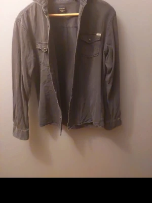Jack & jones skjorta - Jack & jones skjorta i 100%bomull. Enkla knappar som klickar. Färgen är mörk grå. Hör av vid funderingar!