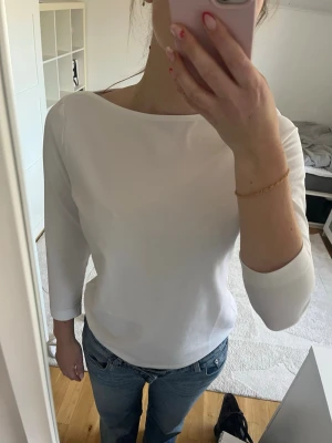 Vit tre kvart topp i bomull - En enkel och stilren vit topp med 3/4 ärm och båt halsringning. Tillverkad i mjuk bomull som känns skön mot huden. Perfekt att matcha med jeans eller kjol för en clean look. Använd 1 gång 