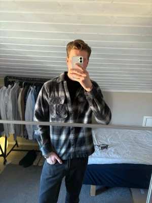 Svartvit rutig overshirt - Säljer en svartvit rutig overshirt i mjukt bomullstyg. Skjortjackan har två bröstfickor med lock, klassisk krage och knäppning framtill. Perfekt lager-på-lager-plagg för en avslappnad streetwear-look.