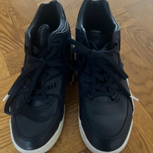 Nike Air Flight 89 – mörkblå skinn – strl 39 - Snygga svarta Nike Air sneakers med högt skaft och vit sula. Skorna har klassisk Nike-logga på sidan, perforerade detaljer och robust design. Perfekta för dig som gillar streetwear och sportig stil.