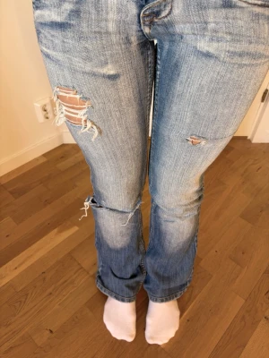 Vintage low waist bootcut jeans (slitna & washed look) - Säljer ett par sjukt snygga vintage jeans med low waist och bootcut fit   Ljusblå denim med en riktigt fin “washed” look och naturliga slitningar. De har hål och fransiga detaljer vid knän och ben som ger en perfekt worn-in och edgy vibe   Bootcut-modellen ger en snygg flare längst ner och tillsammans med den lågmidjade passformen får man en riktigt trendig Y2K-silhuett. Bakfickorna och detaljerna ger jeansen karaktär ✨ Riktigt snygga statement   M men passar mer som S – kolla måtten på bilderna