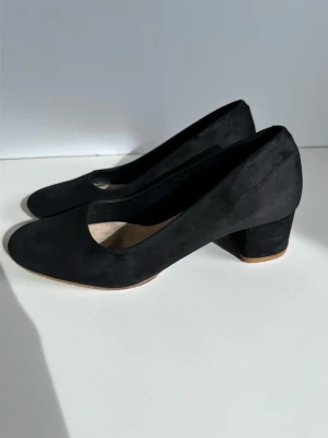 Filippa K - Svarta mockapumps med blockklack - storlek 38 - Eleganta svarta pumps / klackar från Filippa K i storlek 38 i 100% äkta mocka / läder. Skorna har en bekväm blockklack på ca 4-4,5cm och en klassisk design som passar för många tillfällen. Tidlös kvalitetssko som kommer hålla år efter år. Färgen på innersulan är lite avskavd, men inget som syns när den är på. Annars i mycket gott skick, som ny! Nypris 3900:-.
