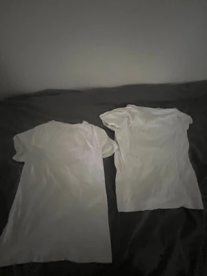 Två vita basic t-shirts - Säljer två klassiska vita t-shirts med rund hals och kort ärm. Perfekta till jeans eller shorts och enkla att matcha med allt. Båda är i mjukt material och har en avslappnad passform.