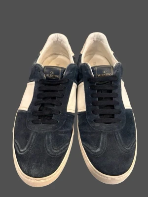 Valentino Flycrew - Valentino Flycrew i färgen Royal Blue. Väldigt snygg modell som passar till det mesta.  Skorna är i mycket fint skick (sömmarna vid sidan av foten har lossnat på båda skor) 3 nitar lossnat, sparsamt använda och väl omhändertagna.  	•	Storlek: 44 	•	Färg: Blå/vit 	•	Material: Mocka & läder 