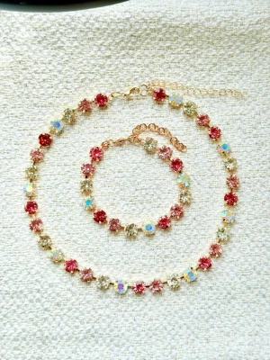 Glittrigt smyckeset med färgglada stenar - Säljer ett halsband och armband med gnistrande stenar i 2 olika rosa, kristall och aurora boreale. De har guldfärgad kedja och justerbar längd. Så fint till bal, bröllop, fest mm Perfekt för dig som gillar färg och vill sticka ut lite extra. Levereras med ask och satinband. 