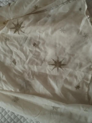 Beige tyg med guldstjärnor - Säljer ett tunt beige tyg med glittriga guldstjärnor i olika storlekar. Tyget har ett mjukt fall och passar perfekt för att skapa egna plagg eller accessoarer. Materialet känns lätt och luftigt( HEMMA SYDD.