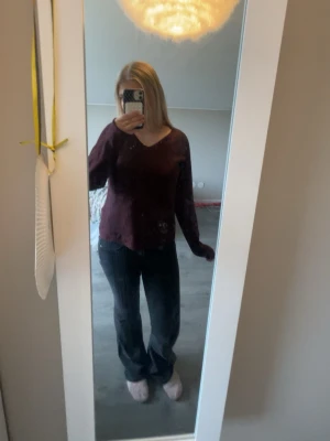 Vinröd stickad tröja med V-ringning - Mysig vinröd stickad tröja med V-ringning och lång ärm. Tröjan har en mjuk struktur och avslappnad passform, perfekt för kyligare dagar. Säljer denna då den inte kommer till användning längre. Tröjan är i storlek XS men skulle säga att den passar mer mot S