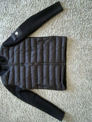 Moncler cardigan - Snygg svart cardigan från Moncler. Jackan har dragkedja framtill, två sidofickor med dragkedja och en patch med Moncler-logga på ena ärmen. Passar för dig som är runt 190cm