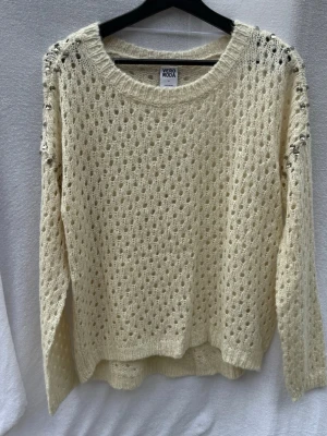 Stickad offwhite tröja Vero Moda (M) - Säljer en stickad offwhite tröja från Vero Moda med hålmönster och rund halsringning. Tröjan har långa ärmar och ribbstickade muddar. Perfekt för lager-på-lager och en avslappnad stil.