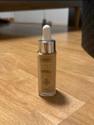 L'Oréal True Match Nude Foundation - Ljus foundation från L'Oréal True Match Nude i nyansen 2-3 Light. Kommer i en glasflaska med pipett och har en lätt, flytande formula med 1% hyaluronsyra för återfuktning. Perfekt för en naturlig look och enkel applicering.