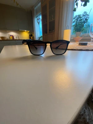 Svarta Ray-Ban solglasögon Wayfarer - Snygga svarta solglasögon från Ray-Ban i klassisk Wayfarer-modell. Bågarna är i plast och har mörka, tonade glas som ger en cool look. Perfekta för dig som vill ha en tidlös och trendig accessoar till sommaren.