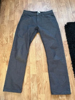 Mörkgrå raka jeans - Säljer ett par mörkgrå jeans med rak passform och klassisk femficksdesign. Jeansen har en enkel look utan slitningar. Perfekta för dig som gillar en clean och stilren stil.