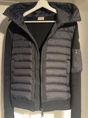Moncler cardiganjacka  - Moncler cardigan i svart. Fint skick och väldigt skön att bära. Stickade ärmar med dunframtill och huva. Perfekt till höst,vinter och vår. Säljs då den inte används längre till användning. Storlek M den passar alla som är runt 175-185cm och väger runt 65-75. Kan även gå ner i pris vid snabb köp! Dm om ni har frågor! 😊 