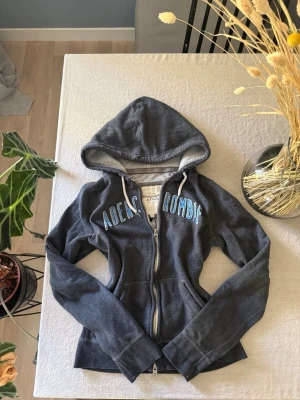 Mörkgrå hoodie från Abercrombie - Mörkgrå hoodie med dragkedja från Abercrombie & Fitch. 