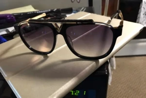 Svarta Louis Vuitton solglasögon - Snygga svarta solglasögon från Louis Vuitton med guldfärgade detaljer och klassisk pilotform. Bågarna har en cool V-detalj framtill och mörka tonade glas. Perfekt accessoar för att lyfta din stil.