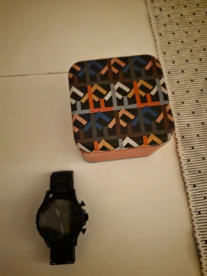 Svart klocka med länkarmband - Snygg svart klocka med robust länkarmband och stor urtavla. Klockan har tydliga siffror och flera knappar på sidan för extra funktioner. Perfekt accessoar för dig som gillar en stilren och modern look.