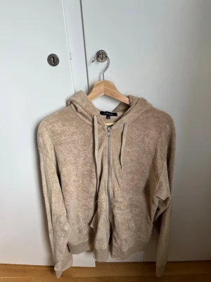 Beige ziphoodie i frotté från Gina Tricot - Mysig beige hoodie i mjuk frotté från Paul & friends. Storlek M, inte använd. 