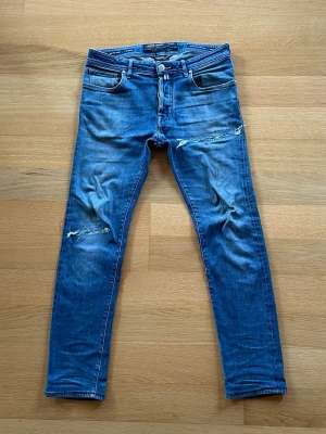 Limited Edition - Ett par limited edition jeans från Jacob Cohën, just detta par är nr 234/342. Jeansen har en lagning på vänster lår och en på höger knä, samt en mindre synlig baktill. Modellen är 688 vilket är en slim fit, även om det inte ser så ut på bilden då jeansen är för stora för mig. Nypriset på dessa byxor var runt 10 000kr och är inte längre tillgängliga. Priset går absolut att diskutera så pruta gärna och skriv om jag ska skicka fler bilder!