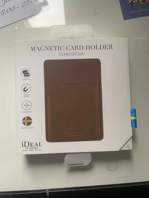 Magnetisk kortplånbok i brunt läder - Snygg och stilren magnetisk kortplånbok från iDeal of Sweden i färgen Como Brown. Plånboken är tillverkad i brunt läder och har ett slimmat design med ett kortfack. Perfekt att fästa på mobilen med stark magnet. Svensk design.