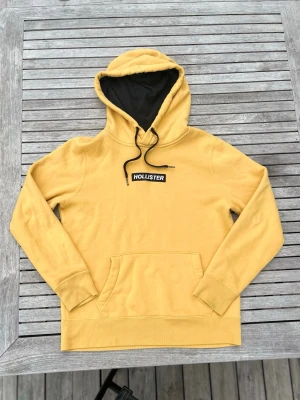 Hollister hoodie  - Säljer denna gula hoodie från Hollister i storlek xs. Hoodien har inga skador eller hål men däremot har den några småfläckar (inget man ser eller lägger märke till) som säkert går att få bort. Bara att höra av sig vid minsta fundering!!