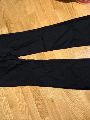Svarta vida byxor - Säljer ett par svarta byxor med rak och vid passform. Byxorna har enkel design utan synliga detaljer eller fickor och är tillverkade i ett mjukt tyg som ser bekvämt ut. Perfekta för en avslappnad stil.