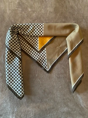 Färgglad mönstrad sjal vintage - Snygg fyrkantig sjal med grafiskt svartvitt mönster, beige och senapsgula fält. Tunn och mjuk, perfekt att knyta runt halsen eller i håret. Materialet känns som silkesmix och ger en lyxig känsla. Passar dig som gillar att sticka ut med accessoarer.