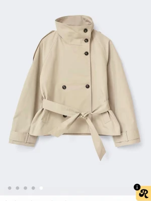 Kort beige trenchcoat med bälte - Trendig trenchcoat i beige från Gina, i storlek XS. Helt oanvänd och prislappen finns kvar. Meddela mig gärna vid funderingar 💕 Pris kan diskuteras 