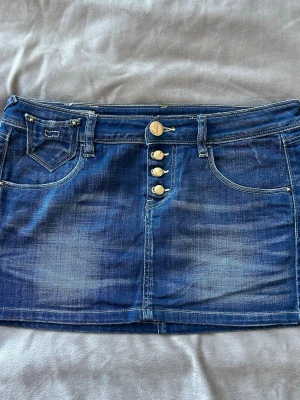 Kort Lågmidjad Vintage Jeanskjol - Jätte gullig jeanskjol vintage med detaljer på fram och baksidan 💕 Midjemått: ca 39cm Nederkant (bredd längst ner): ca 45cm  Alla bud över 200kr accepteras - säg till om du har några frågor :D  #vintage #y2k #jeanskjol #sommar #vintagedenim #denim #secondhand #preloved #lowrise #y2kvintage #miniskirt #minikjol