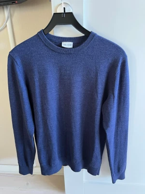 Mörkblå tröja från John Henric - Klassisk mörkblå tröja från John Henric med rund halsringning och ribbade muddar vid ärmslut och nederkant. Tröjan är enkel och stilren, perfekt för lager på lager och passar till det mesta. Materialet ser ut att vara mjukt och bekvämt. 