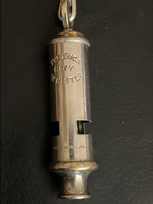 Silverfärgad visselpipa från J. Hudson - Säljer en klassisk silverfärgad visselpipa från J. Hudson & Co, modell 'The EMCA City Whistle'. Tillverkad i metall med rund form och ingraverad text. Perfekt som accessoar till nyckelknippan eller väskan.