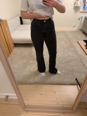 Svarta bootcut jeans med knappar - Säljer ett par svarta bootcut jeans med hög midja och knappgylf. Jeanstyg med lite stretch. Sitter jättefint och passar nästan alla. Från Gina tricot