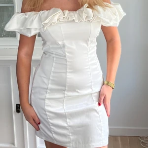 Student klänning - Köp via instabox!! Säljer en vit, axelbandslös klänning med volang upptill. Aldrig använd!!Perfekt till student och midsommar!!Klänningen har en tight passform och är sydd i ett glansigt material som ger en elegant look. Står ingen storlek men skulle uppskatta den som en S
