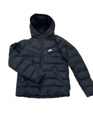Nike bomberjacka i svart (Nypris: 599 kr) - Czarna kurtka puchowa Nike w rozmiarze 170 (dziecięca). Ciepła i wygodna z kapturem, idealna na jesień i zimę. Kurtka zapinana jest z przodu na zamek błyskawiczny i posiada kieszenie zapinane na guzik. Stan: używana, z niewielkimi przebarwieniami (patrz zdjęcie), ale nadal nadaje się do użytku. Materiał: 100% poliester.  Svart dunjacka från Nike i storlek 170 (barn). Varm och skön med huva, perfekt för höst och vinter. Jackan har dragkedja framtill och fickor med knapp.