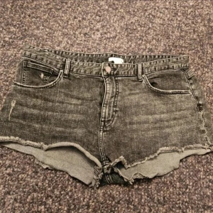 Grå jeansshorts med rå kant från H&M 44 - Säljer ett par grå denimshorts från H&M i storlek 44. De har en klassisk femficksmodell, råa och fransiga kanter nertill samt knapp- och dragkedjestängning. Perfekta för en avslappnad stil och passar till allt.  Kan även hämtas I Partille  E5