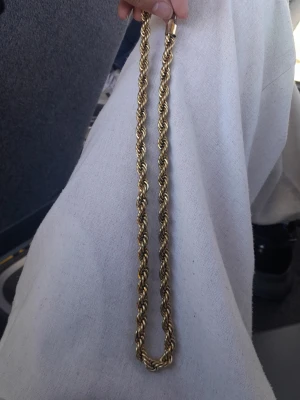 Guldfärgat tvinnat halsband - Snyggt halsband i guldfärg med tvinnad kedja som ger en cool och trendig look. Halsbandet har en robust känsla och passar perfekt till att lyfta din outfit. Materialet ser ut att vara metall med en glansig finish.