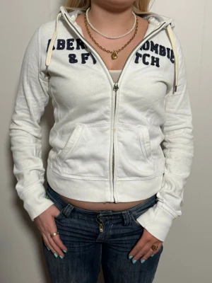 Vintage Abercrombie & Fitch hoodie - En snygg vit  vintage ziphoodie från märket Abercrombie & Fitch. Perfekt nu till våren och varmare värder. Size M. Skick 9/10 OBS UNISEX. Modellen är 164cm (Tjej)